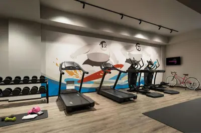 a gym with cardio equipment and a wall mural at MOXY Tokyo Kinshicho in Tokyo