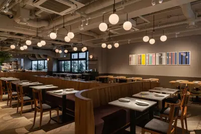 a restaurant with wooden tables and chairs and lights at THE KNOT TOKYO Shinjuku in Tokyo