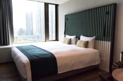 a bedroom with a large bed with a large window at THE KNOT TOKYO Shinjuku in Tokyo
