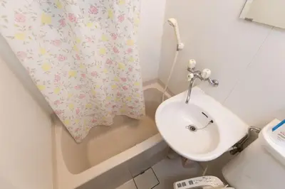 a bathroom with a sink and a shower curtain at Shinjuku Apartment 102 in Tokyo