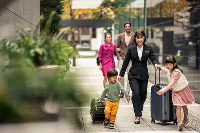 a family walking down a sidewalk with their luggage at Four Seasons Hotel Tokyo at Marunouchi in Tokyo