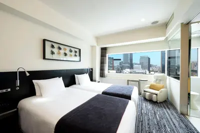 a hotel room with two beds and a window at remm Akihabara in Tokyo