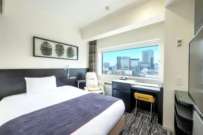 a hotel room with a bed and a desk and a window at remm Akihabara in Tokyo