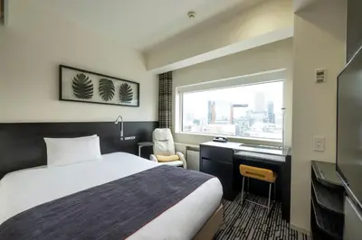 a hotel room with a bed and a desk and a window at remm Akihabara in Tokyo