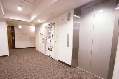a hallway of an office with white walls and elevators at Hearton Hotel Higashi-Shinagawa in Tokyo