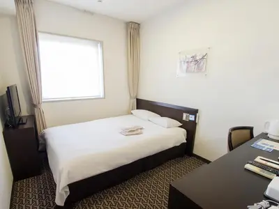 a hotel room with a bed and a desk and a window at Hearton Hotel Higashi-Shinagawa in Tokyo