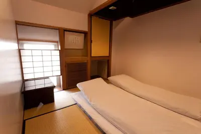 a small bedroom with two beds and a window at Kimi Ryokan in Tokyo