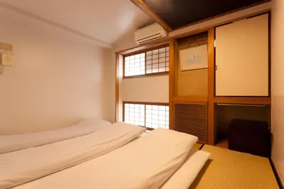 two beds in a room with a window at Kimi Ryokan in Tokyo