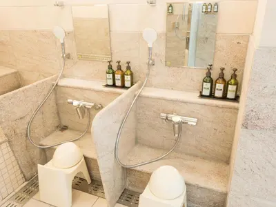 a bathroom with a shower and a toilet and bottles of wine at Glansit Akihabara in Tokyo