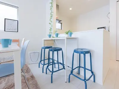a kitchen with three blue stools in front of a counter at THE HOUSE Ikebukuro Sugamo in Tokyo