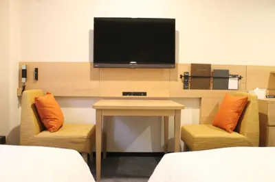 a room with a tv and two chairs and a table at Nishitetsu Inn Shinjuku in Tokyo