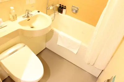 a bathroom with a toilet and a sink and a tub at Nishitetsu Inn Shinjuku in Tokyo