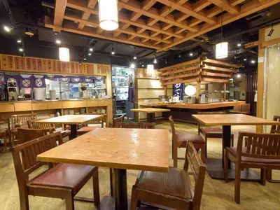 a restaurant with wooden tables and chairs and a counter at Nishitetsu Inn Shinjuku in Tokyo
