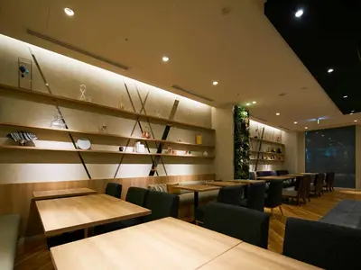 a dining room with wooden tables and chairs and a wall at Hotel Intergate Tokyo Kyobashi in Tokyo