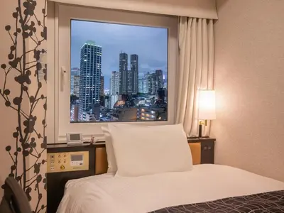 a bedroom with a window with a view of a city at APA Hotel & Resort Nishishinjuku Gochome Ekimae Tower - Formerly APA Hotel & Resort Nishishinjuku Gochome Eki Tower in Tokyo