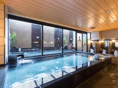 a large swimming pool in a building with a large window at APA Hotel & Resort Nishishinjuku Gochome Ekimae Tower - Formerly APA Hotel & Resort Nishishinjuku Gochome Eki Tower in Tokyo