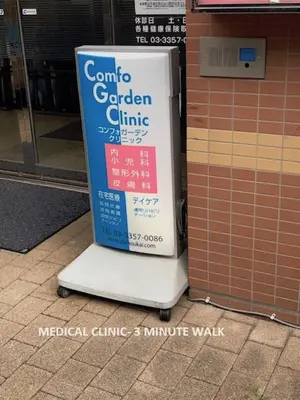 a sign sitting on the sidewalk next to a building at Shinjuku Central Apartment 203 in Tokyo