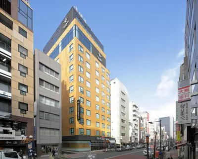 a tall yellow building on a city street at Candeo Hotels Tokyo Shimbashi in Tokyo