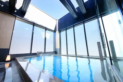 a swimming pool in a building with windows at Candeo Hotels Tokyo Shimbashi in Tokyo