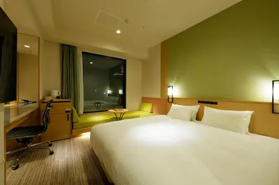 a hotel room with a bed and a desk and a window at Candeo Hotels Tokyo Shimbashi in Tokyo