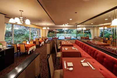 a restaurant with red tables and chairs and windows at Tokyo Prince Hotel in Tokyo