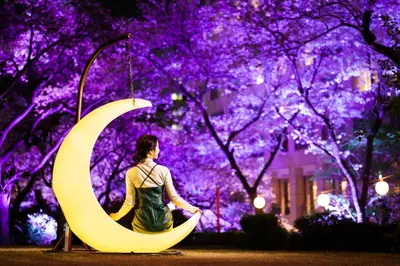 a woman sitting next to a crescent moon at night at Grand Prince Hotel Takanawa in Tokyo