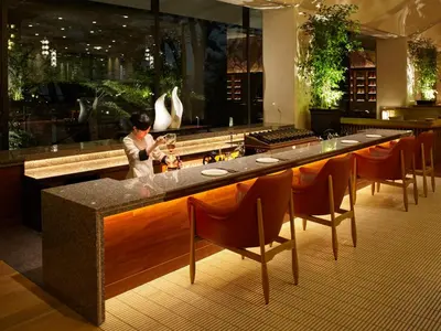 a woman standing at a bar in a restaurant at Grand Prince Hotel Shin Takanawa in Tokyo