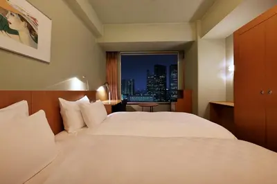 a bedroom with a large white bed with a city view at Shinagawa Prince Hotel in Tokyo