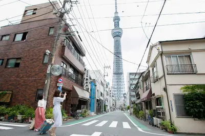 two women crossing a street with the tv tower in the background at La Krasse Sumida in Tokyo