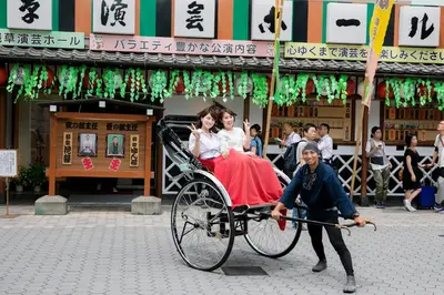 a man pulling a rickshaw with two people on it at La Krasse Sumida in Tokyo