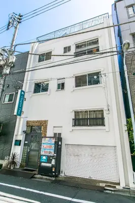 a white building with a door and a street at Hostel Chapter Two Tokyo in Tokyo