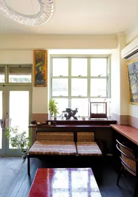 a living room with a bench and a large window at Hostel Kura in Tokyo