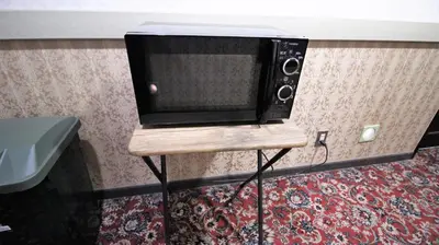 a microwave sitting on a stand in a room at Royal Hotel Shinokubo in Tokyo
