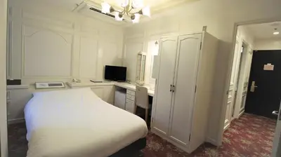 a bedroom with a white bed and a desk and a computer at Royal Hotel Shinokubo in Tokyo