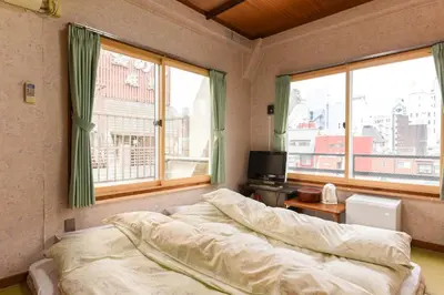 a bedroom with a bed and two large windows at Ryokan Mikawaya in Tokyo