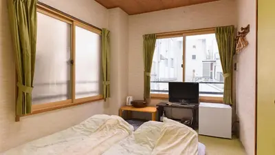 a bedroom with a bed and a tv and a window at Ryokan Mikawaya in Tokyo