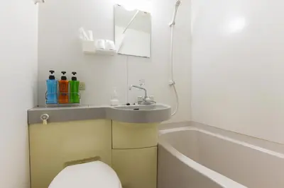 a bathroom with a sink and a toilet and a tub at Ryokan Mikawaya in Tokyo