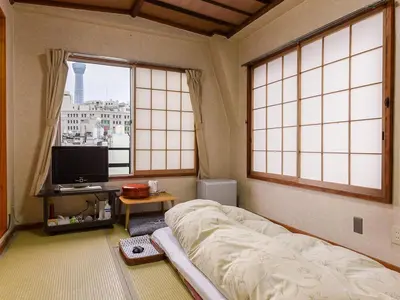 a bedroom with a bed and a tv and windows at Ryokan Mikawaya in Tokyo