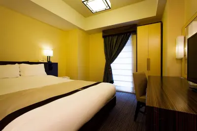 a bedroom with a bed and a desk and a window at Hotel Monterey Hanzomon in Tokyo