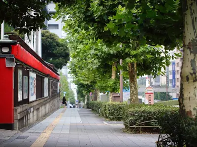 a sidewalk with trees and a red train on it at Hotel Monterey Akasaka in Tokyo
