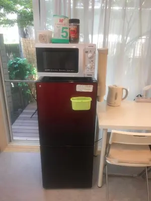 a microwave on top of a refrigerator next to a table at Tokyo Art House in Tokyo