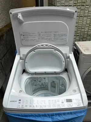 a white toilet with its seat up in the street at Tokyo Art House in Tokyo