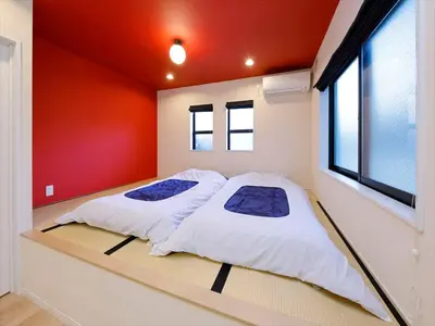two beds in a room with a red wall at COTO Tokyo Shibuya 3 in Tokyo