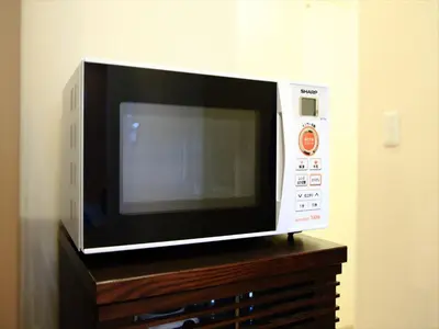 a microwave oven sitting on top of a wooden dresser at COTO Tokyo Shibuya 3 in Tokyo
