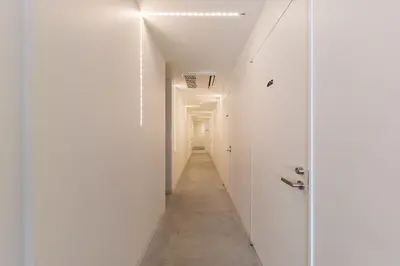 a hallway with white walls and a white door at &AND HOSTEL AKIHABARA in Tokyo