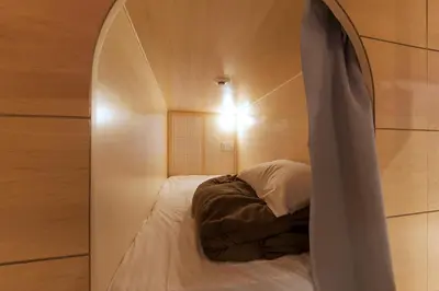 a bed in a room with an arched window at &AND HOSTEL AKIHABARA in Tokyo