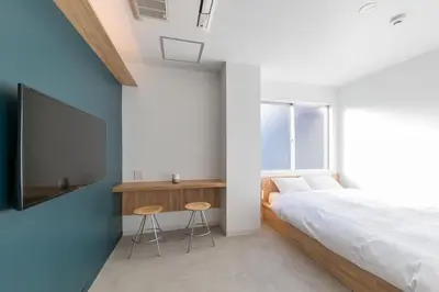 a bedroom with a bed and a tv and stools at &AND HOSTEL AKIHABARA in Tokyo