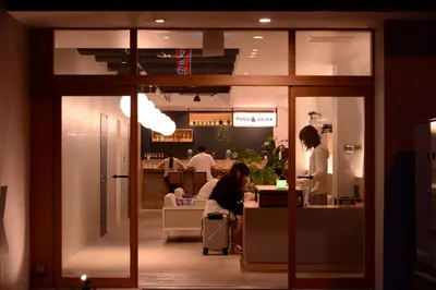 a woman sitting at a counter in a restaurant at &AND HOSTEL AKIHABARA in Tokyo