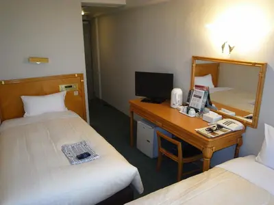 a hotel room with two beds and a desk with a computer at Hotel Kizankan in Tokyo