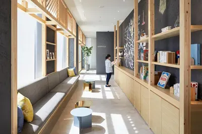 a person standing in a room with a book shelf at OMO5 Tokyo Otsuka by Hoshino Resorts in Tokyo